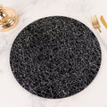 Black plate with abstract white line design on a marble surface.