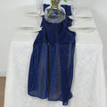 Navy blue glitter table runner on a white tablecloth with elegant glassware.