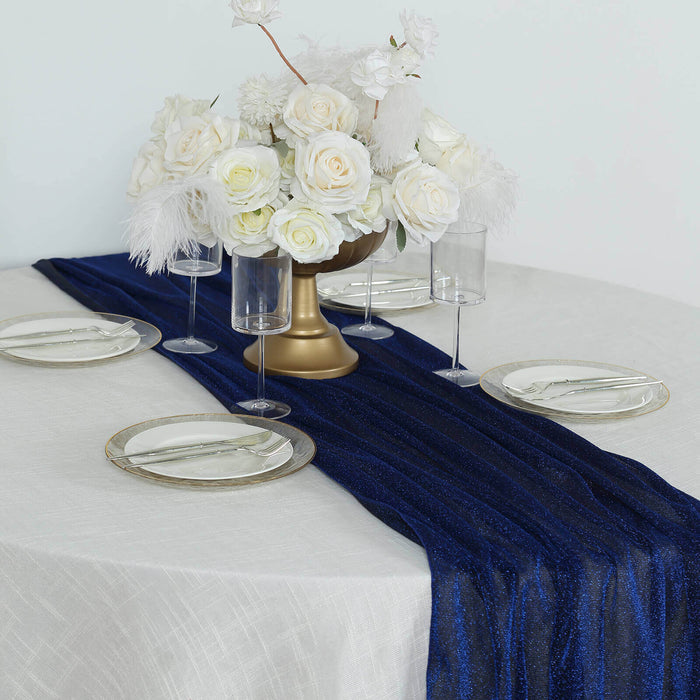 Elegant table setting with navy runner, white flowers, and glassware.