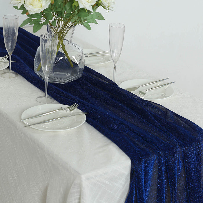 Navy blue glitter table runner on a white table setting with glassware and plates.