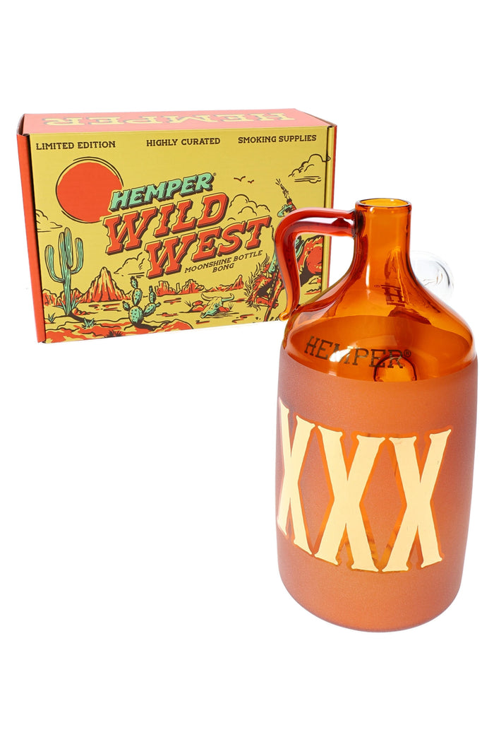 Hemper Wild West moonshine bottle glass bong angled in front of its yellow desert-themed box, ready for online smoke shop product display.