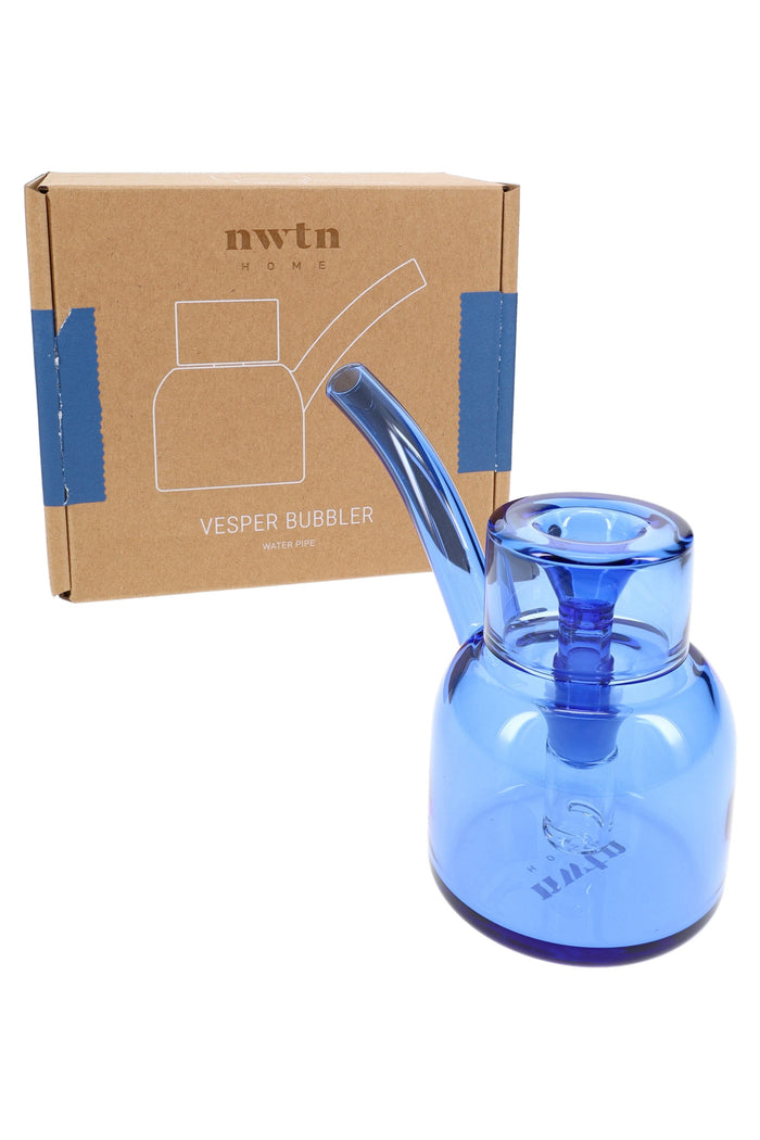 Lapis blue NWTN Vesper glass bubbler in front of branded NWTN Home box, showing gift-ready tabletop bong packaging.