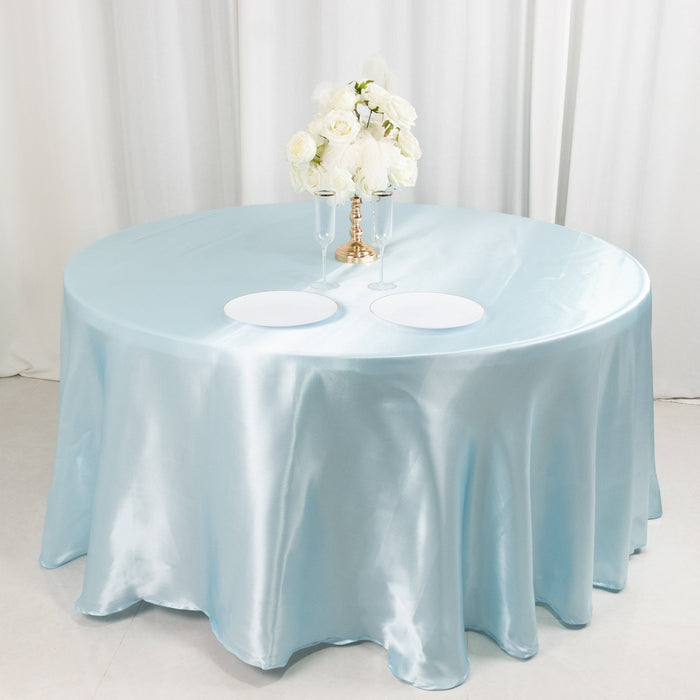 Round table with a light blue satin tablecloth and floral centerpiece.